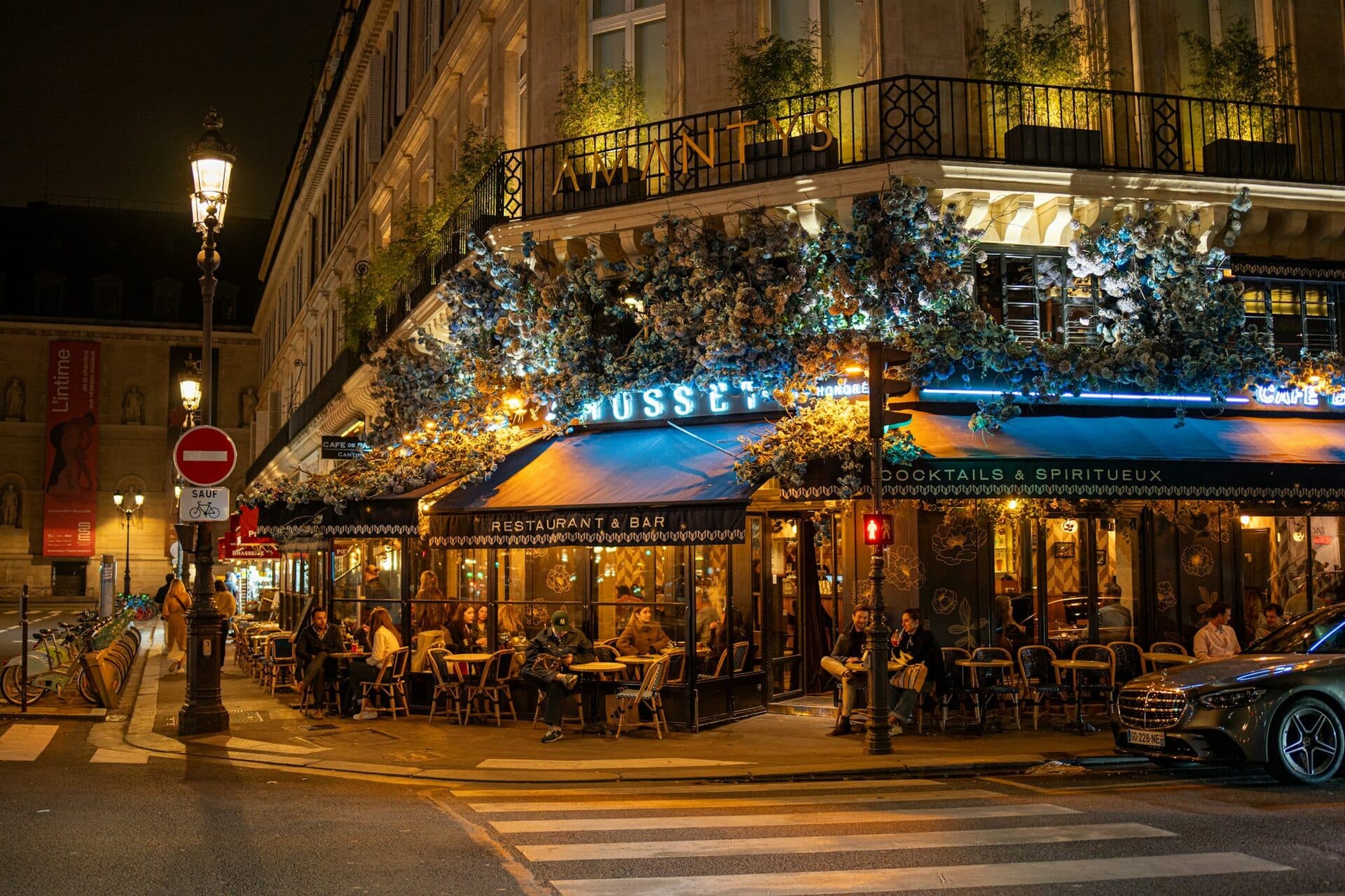 Bistrot parisien eclaire la nuit avec terrasse animee et ambiance chaleureuse